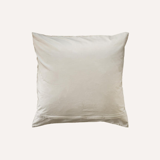 A plain, square, beige cushion with a smooth fabric surface, shown against a light background.