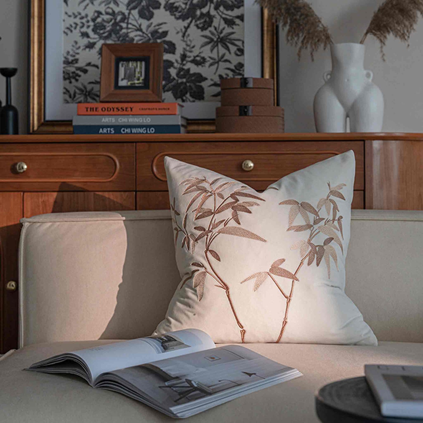 Elegant gold bamboo embroidered cushion with white background on white sofa.