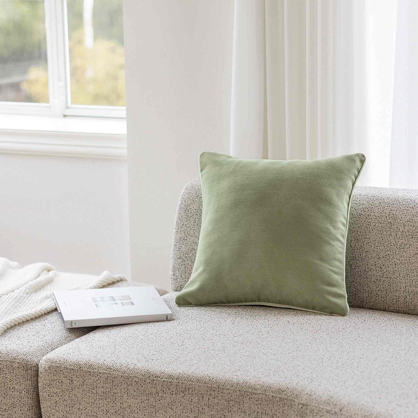 Mint green herringbone, white wrapped chenille cushion on grey sofa.