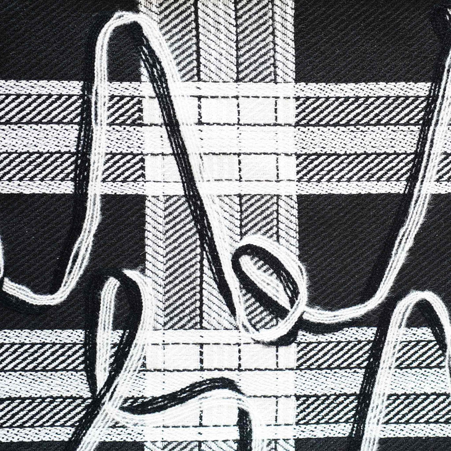 A black and white plaid and ribbon cushion cover.