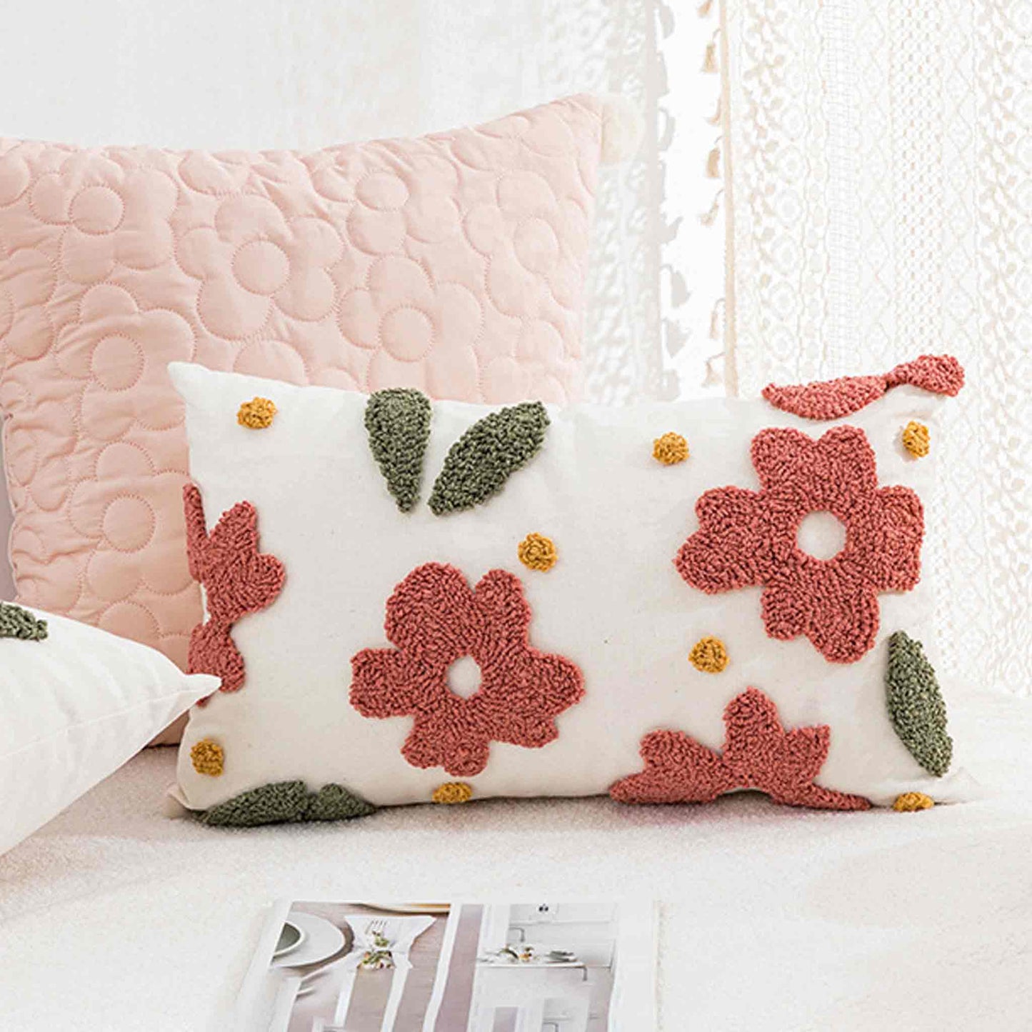 Decorative cushion with floral pattern on a white sofa, accompanied by a pink cushion.