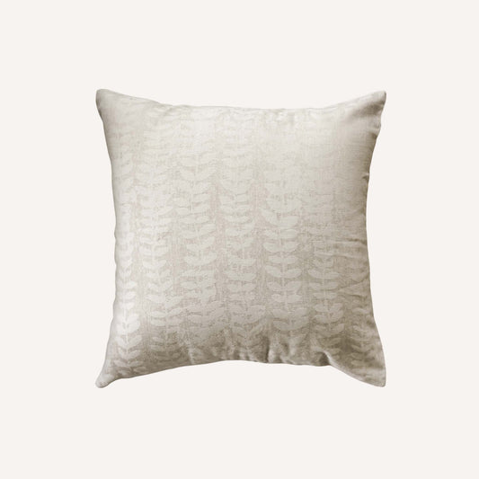 Square beige cushion with a subtle, textured leaf pattern on a plain background.