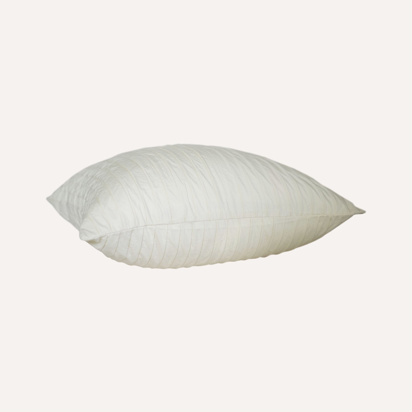 A white cushion with an elegant pleated design adds texture and style to any bedding arrangement.