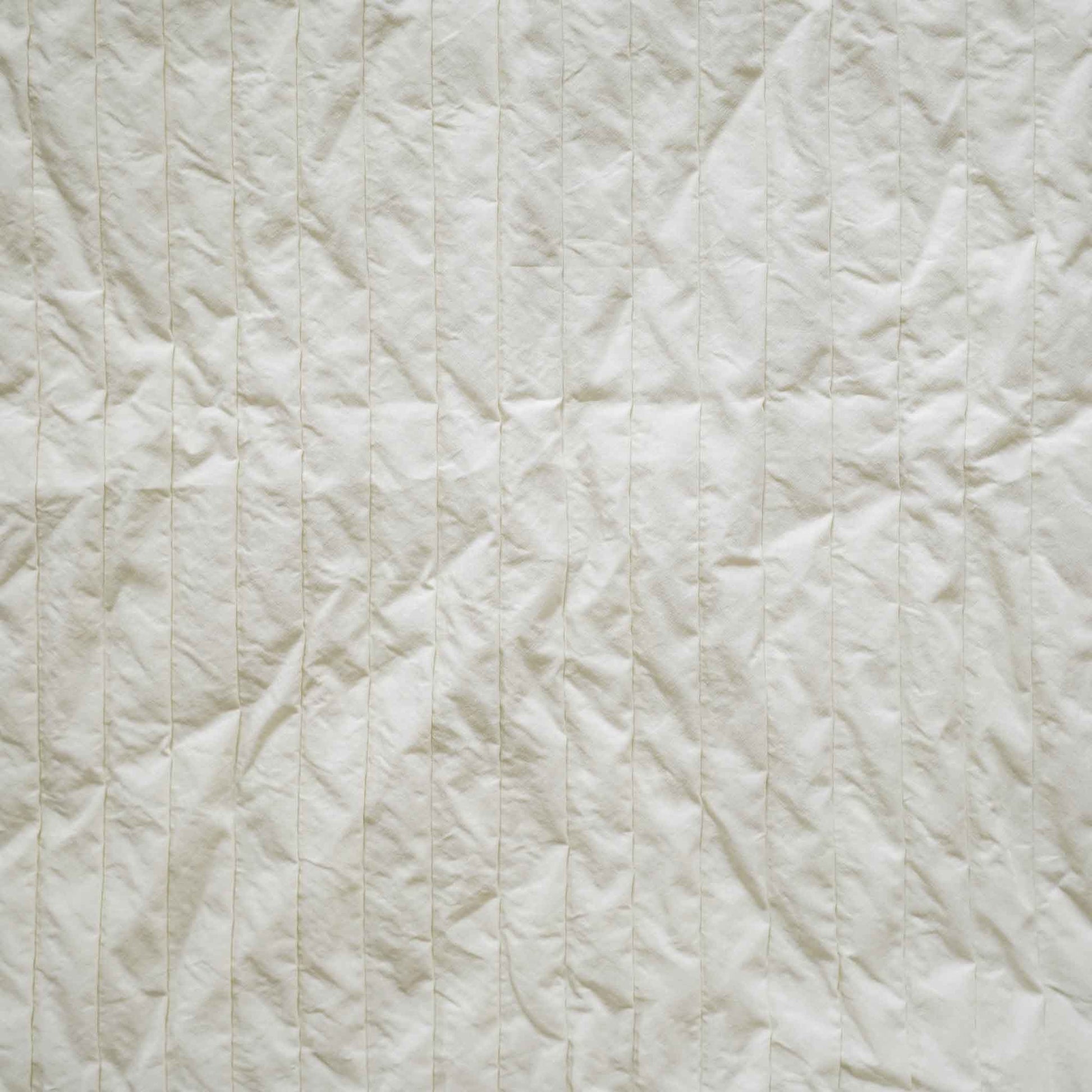 A white cushion with an elegant pleated design adds texture and style to any bedding arrangement.