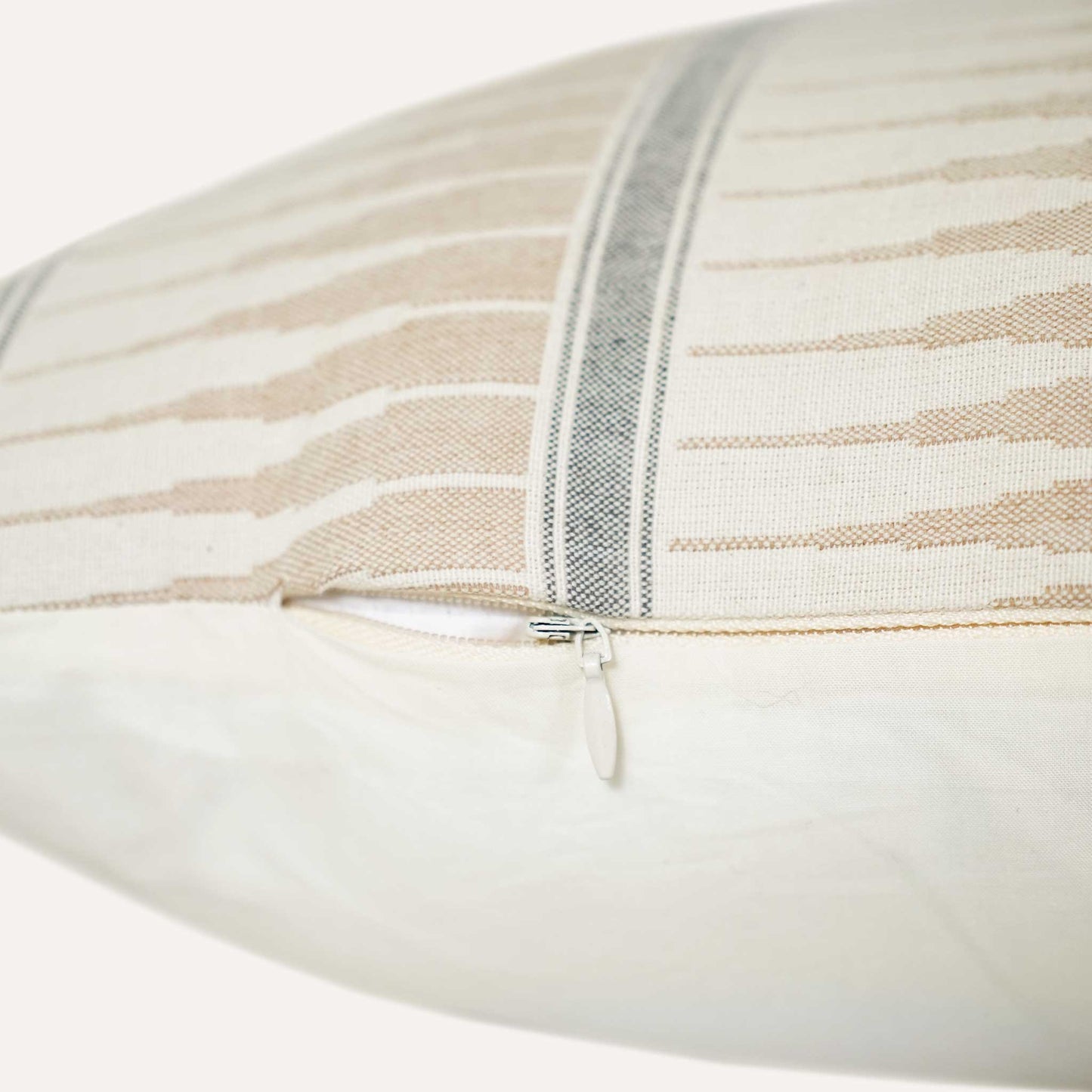 Close-up of the invisible zip on the grey beige striped lumbar cushion.