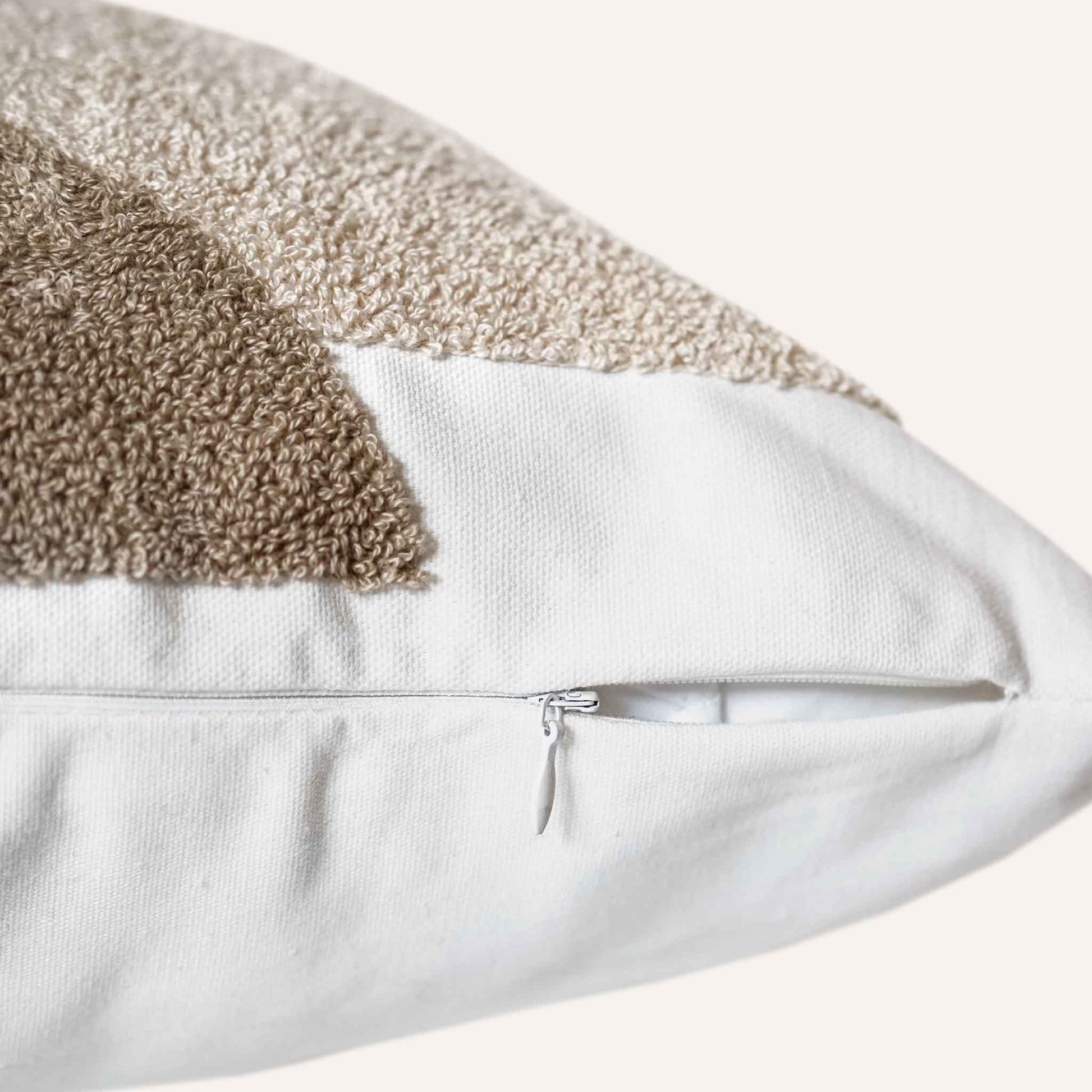 Close-up of the invisible zip on the black beige tufted cushion.