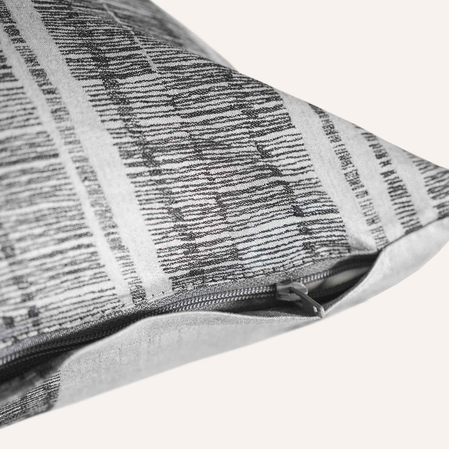 Close-up of the invisible zip on the grey and black patterned lumbar cushion.