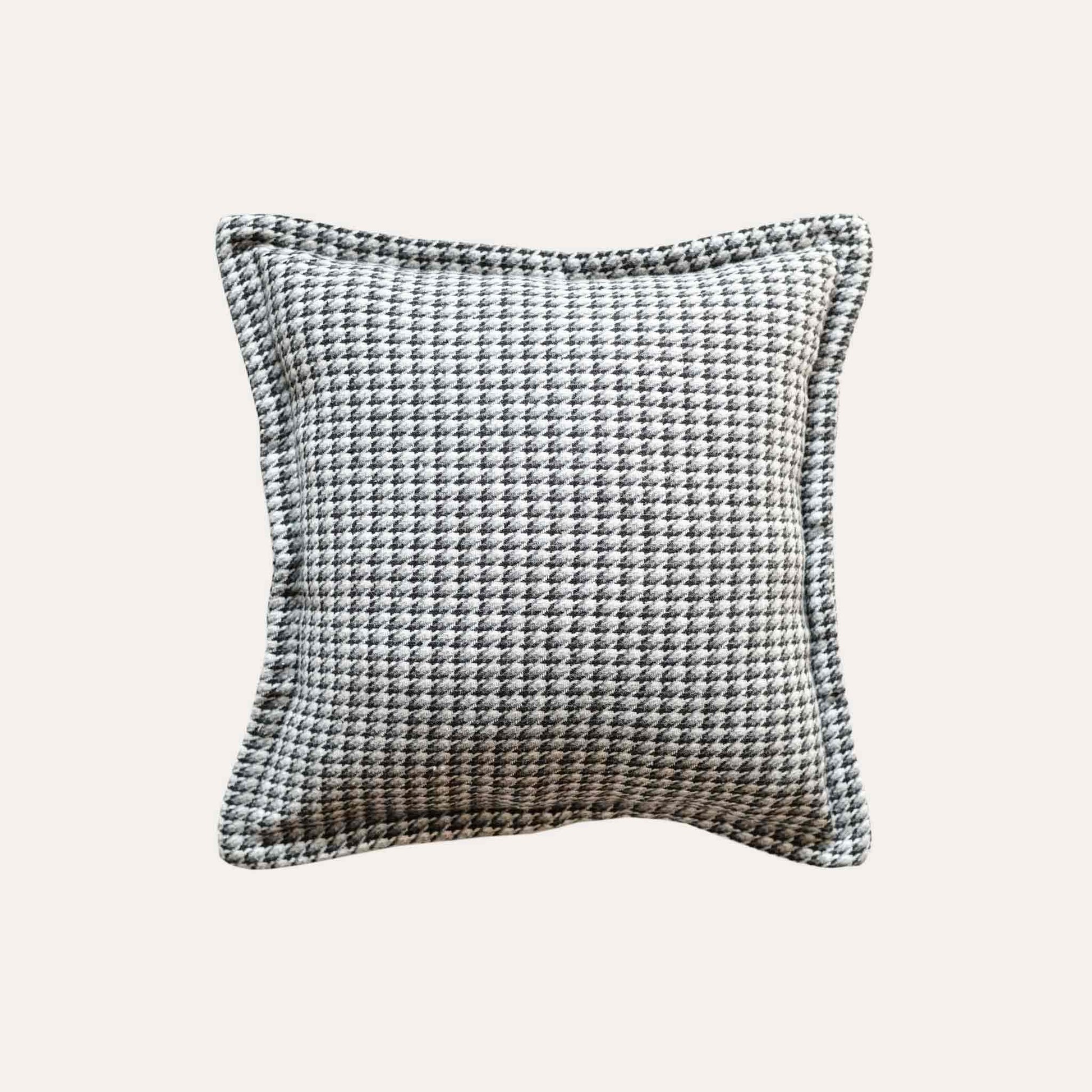A black and grey checkered cushion cover featuring a houndstooth pattern with wide edges.