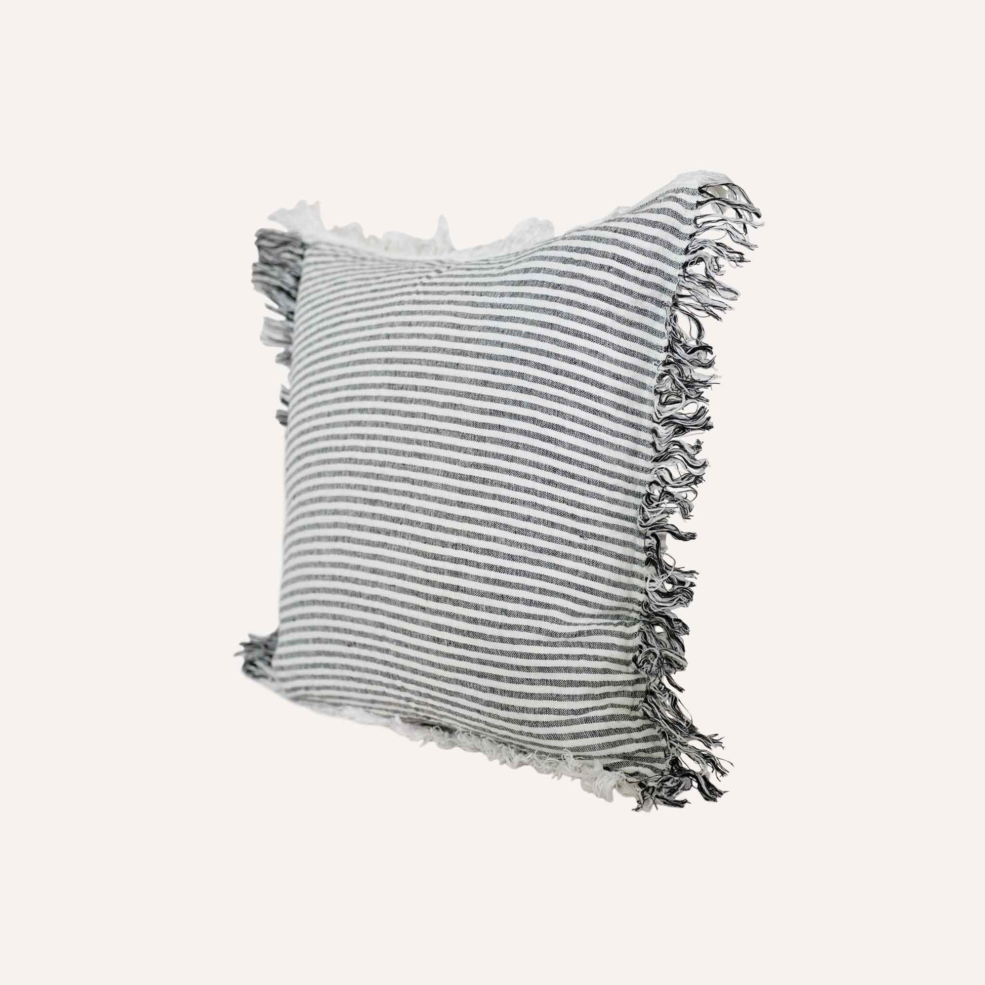 Black and white stripes with a decorative cushion with fringed edges add texture and style to the setting.
