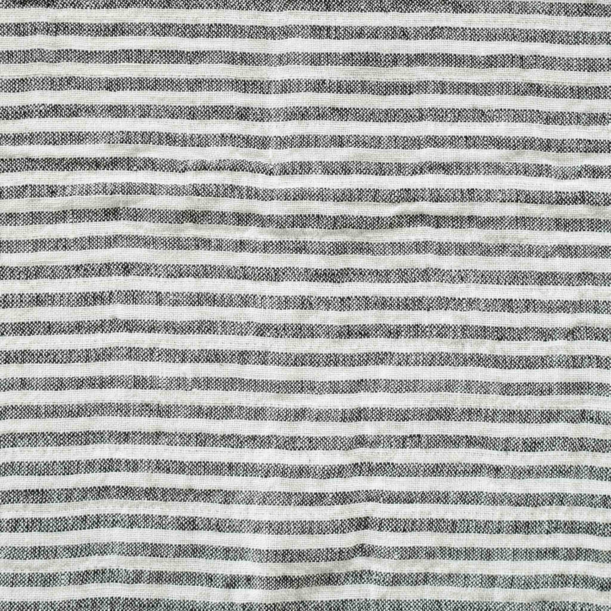 Black and white stripes with a decorative cushion with fringed edges add texture and style to the setting.