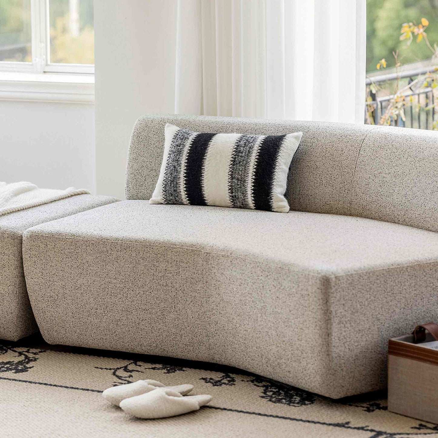 Black and white striped woolen decorative cushion cover on beige sofa.