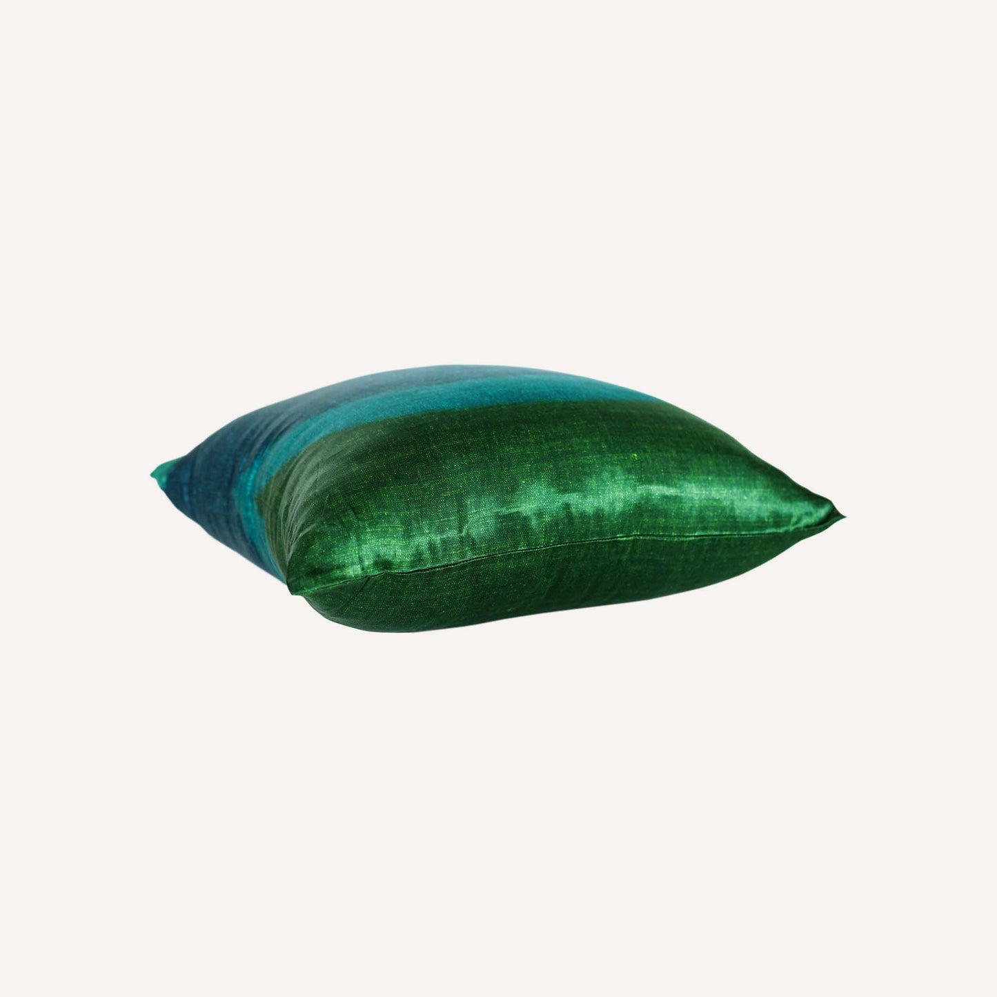 The decorative cushion features a vibrant green and blue tie-dye design in a silk silky material.