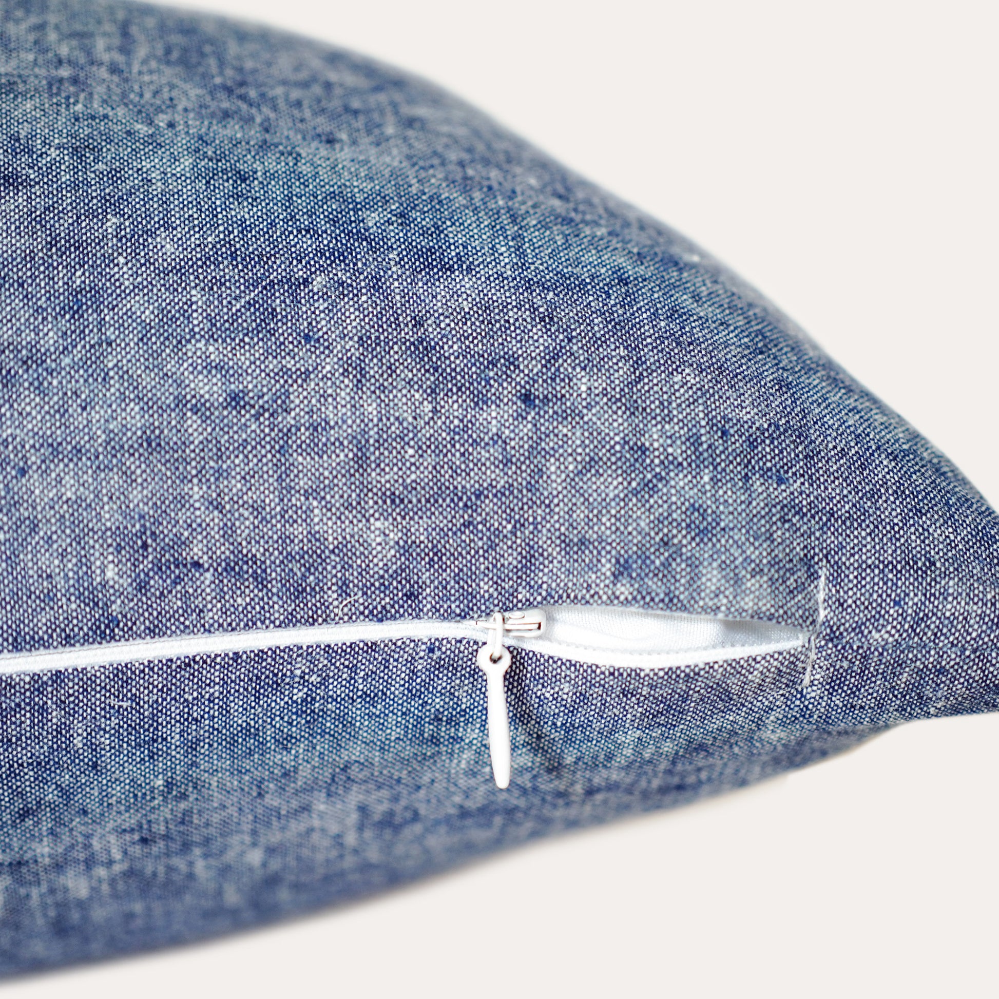 Close-up of the invisible zip on the lumbar cushion in white stripe with blue background.