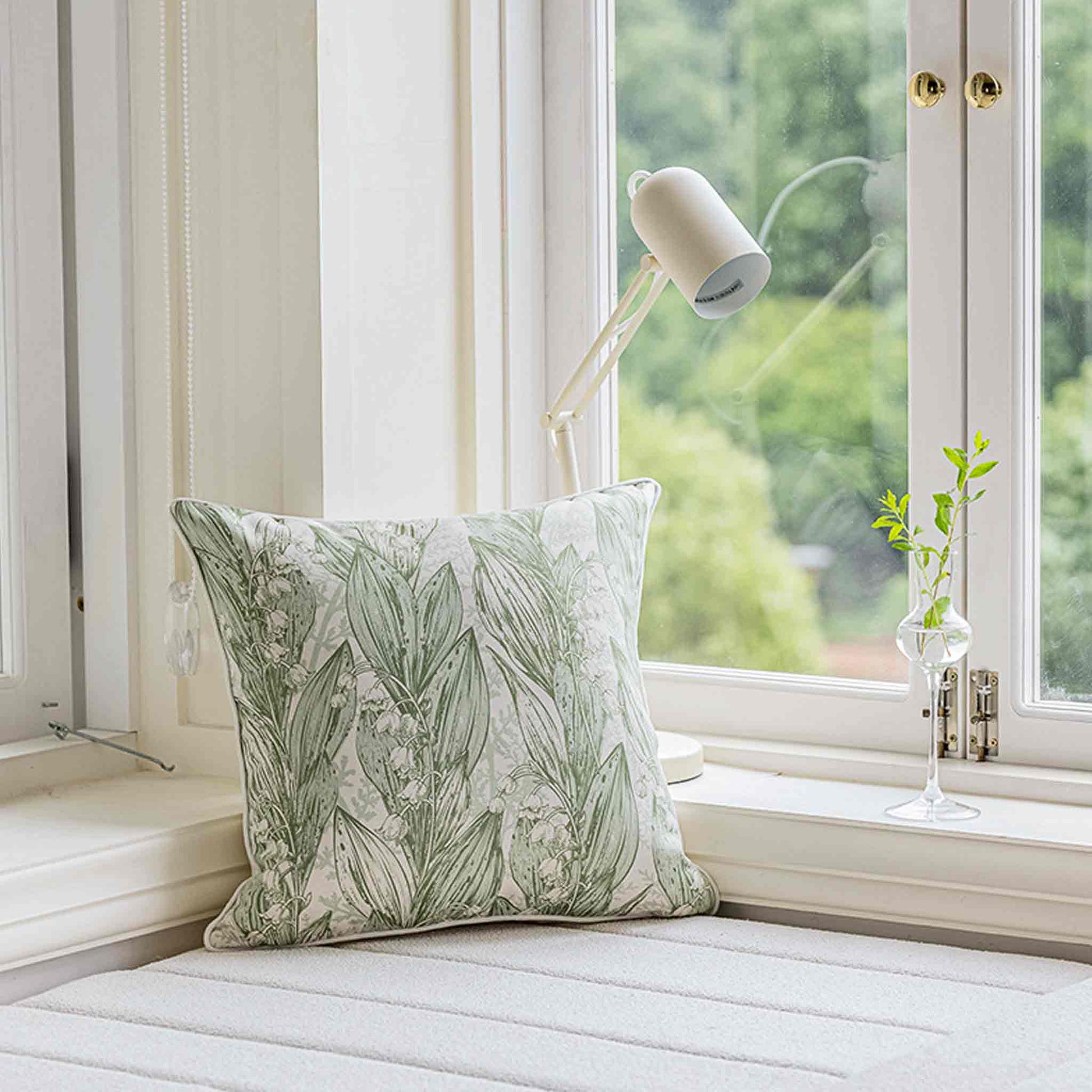 Green lily of the valley botanical floral print cushion cover on sofa.