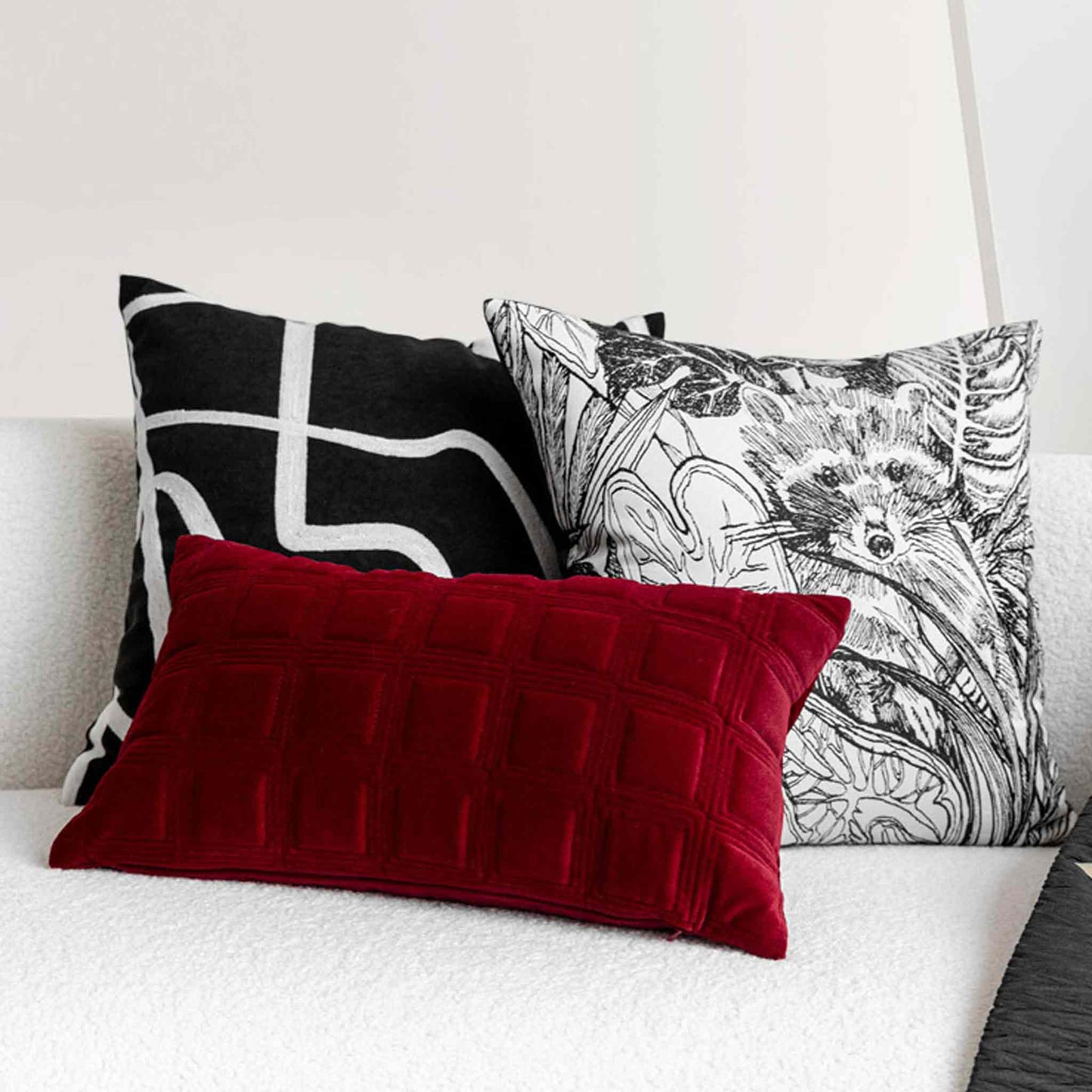 Decorative cushions on sofa; one red, one black with white pattern, one with animal sketch.