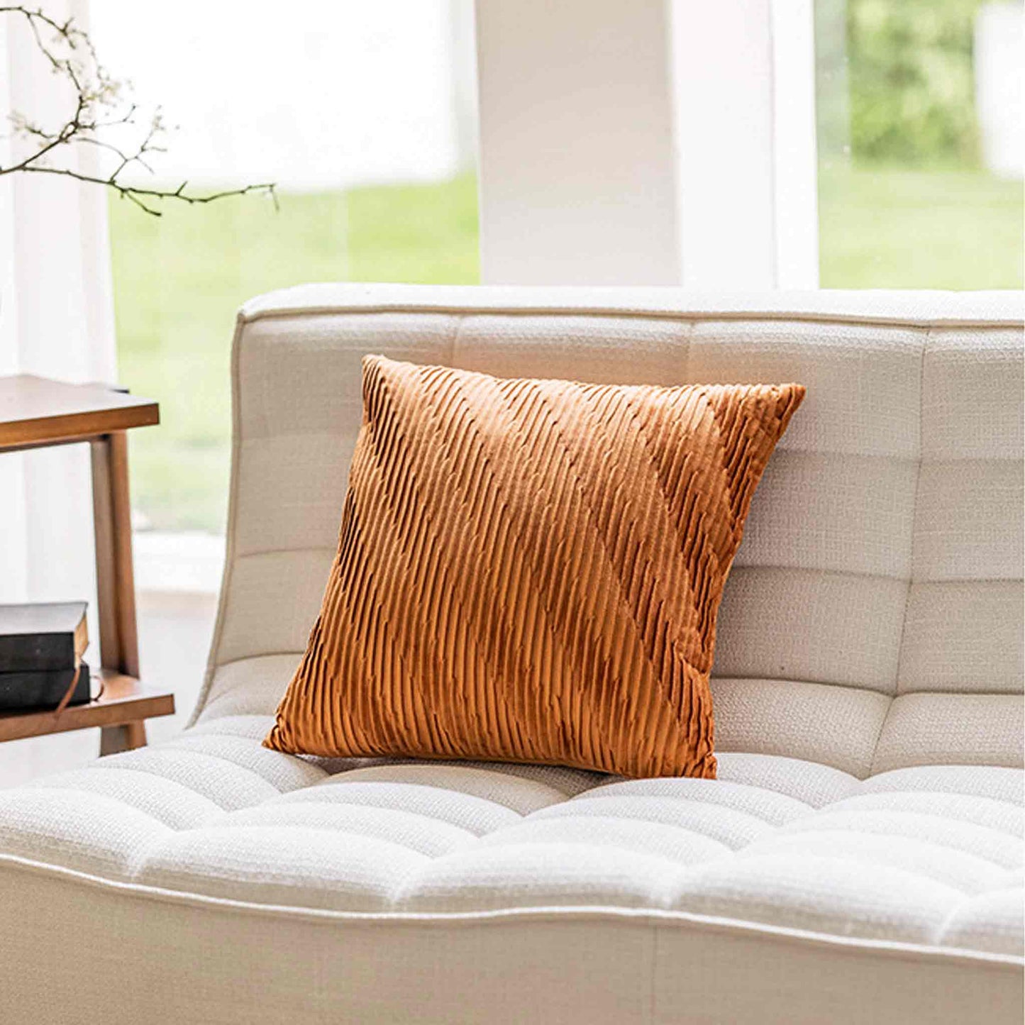 Velvet pumpkin orange cushion covers with pleated design and smooth texture on white sofa.