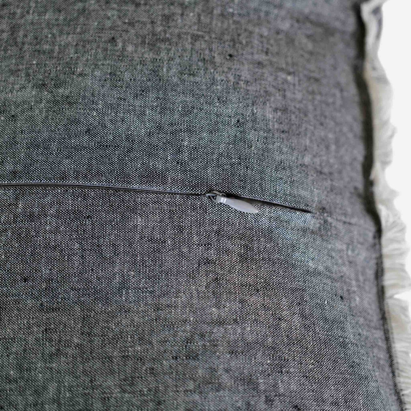 Close up of the invisible zip on the dark grey cushion.