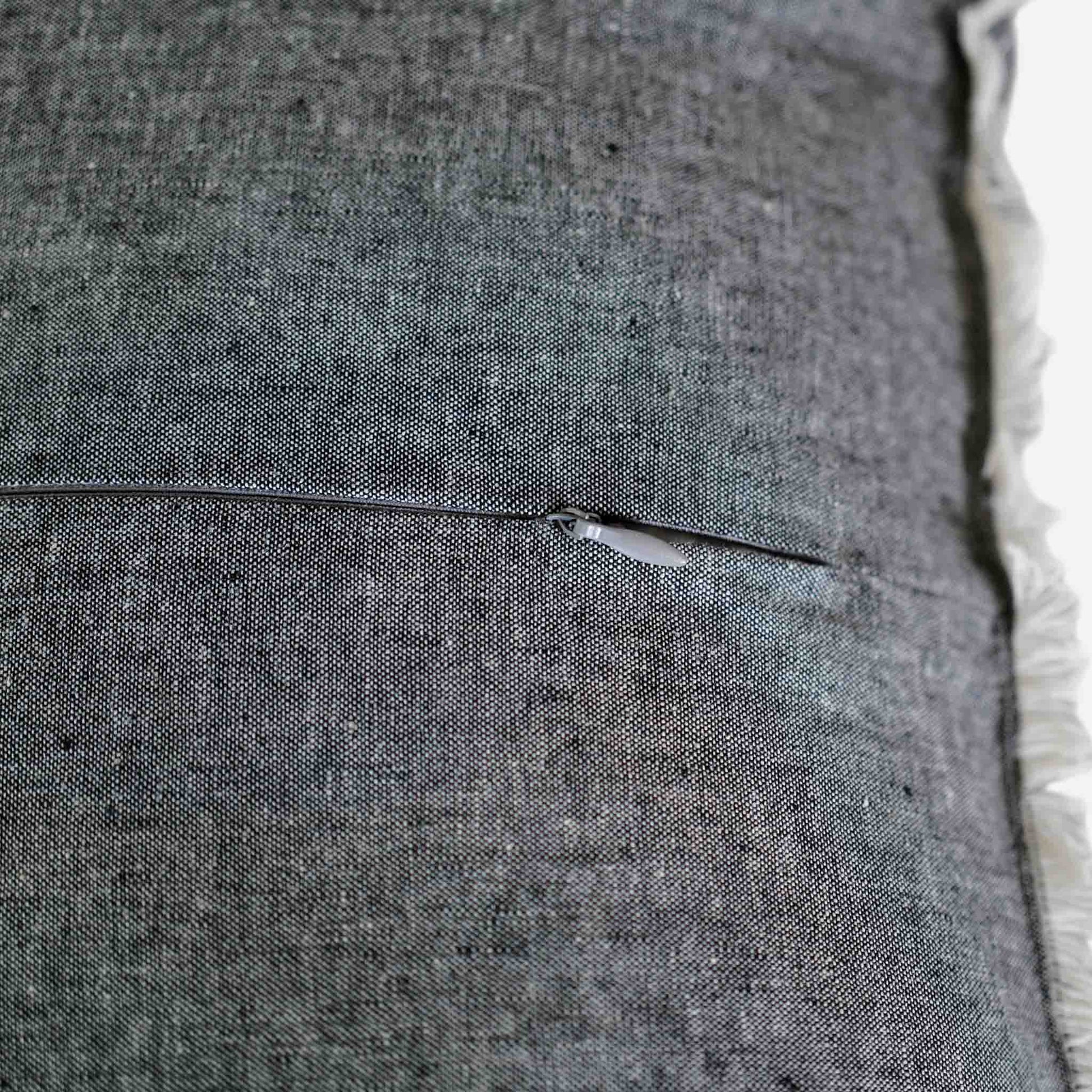 Close up of the invisible zip on the dark grey cushion.