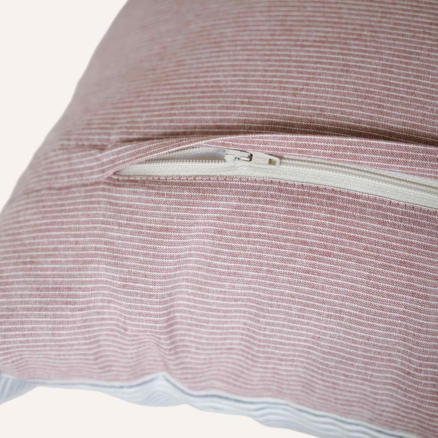 Close up of the invisible zip in the coral red striped cushion.
