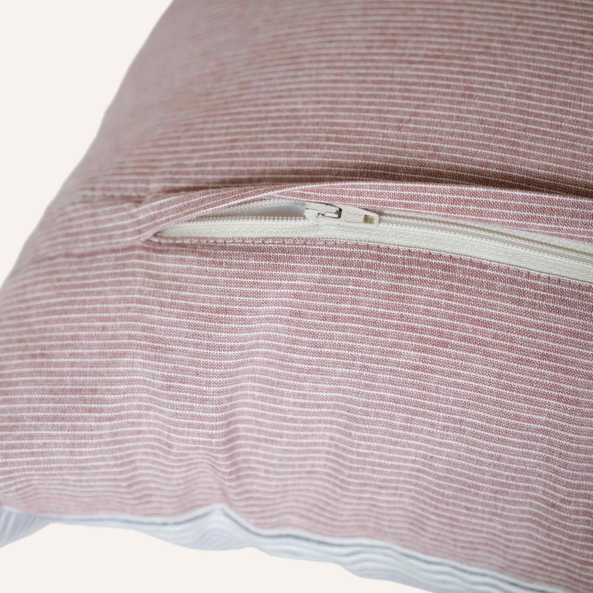 Close up of the invisible zip in the coral red striped cushion.