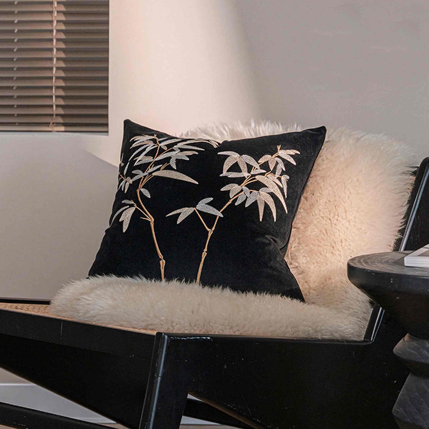 Elegant gold bamboo embroidered cushion cover with black background on chair.