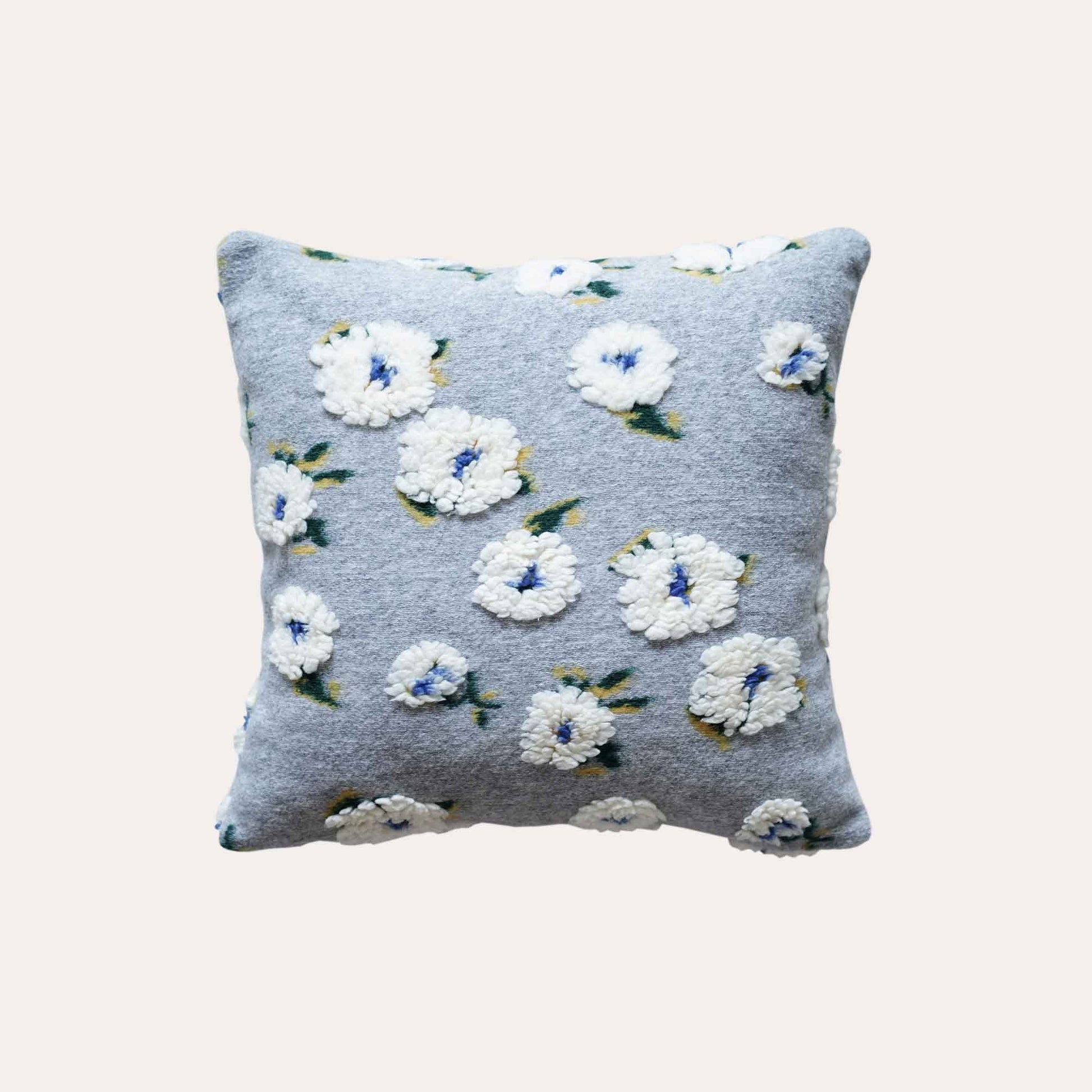 Embellished with delicate tufted white flowers in a soft textured gray cushion cover.