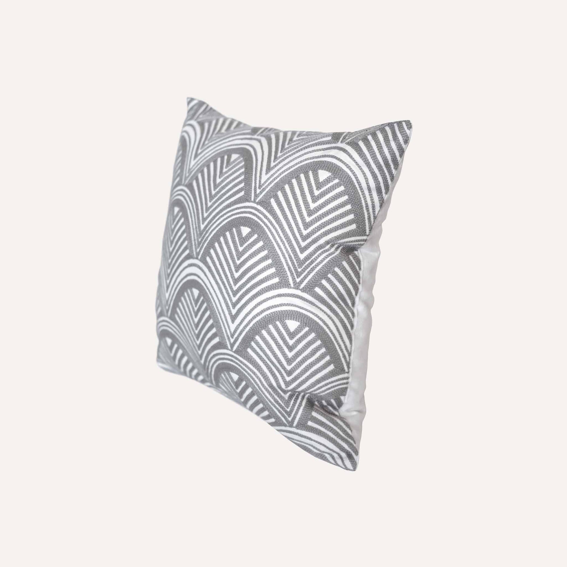 The grey and white scalloped embroidery patterned cushion shows off decorative design and texture.