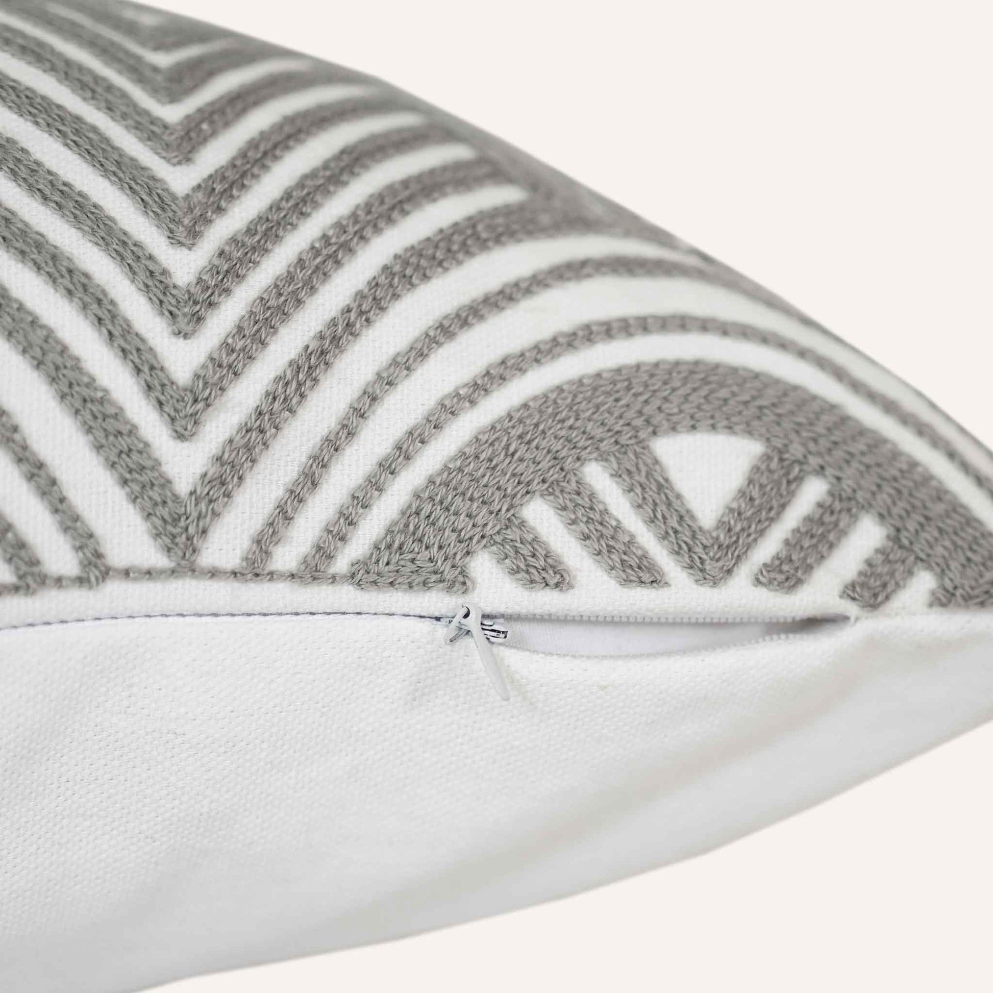 Close-up of the invisible zip on the grey-white scalloped pattern cushion.