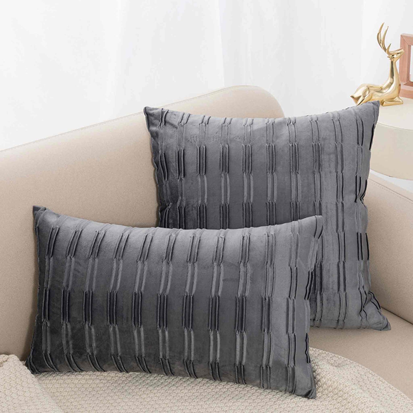 Dark grey pleated velvet cushion covers on sofa.