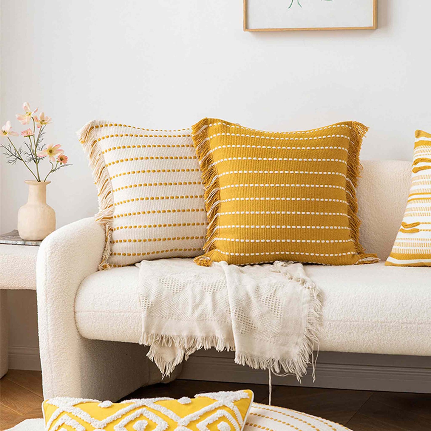 White and yellow bohemian woven tassel cushions on white sofa.