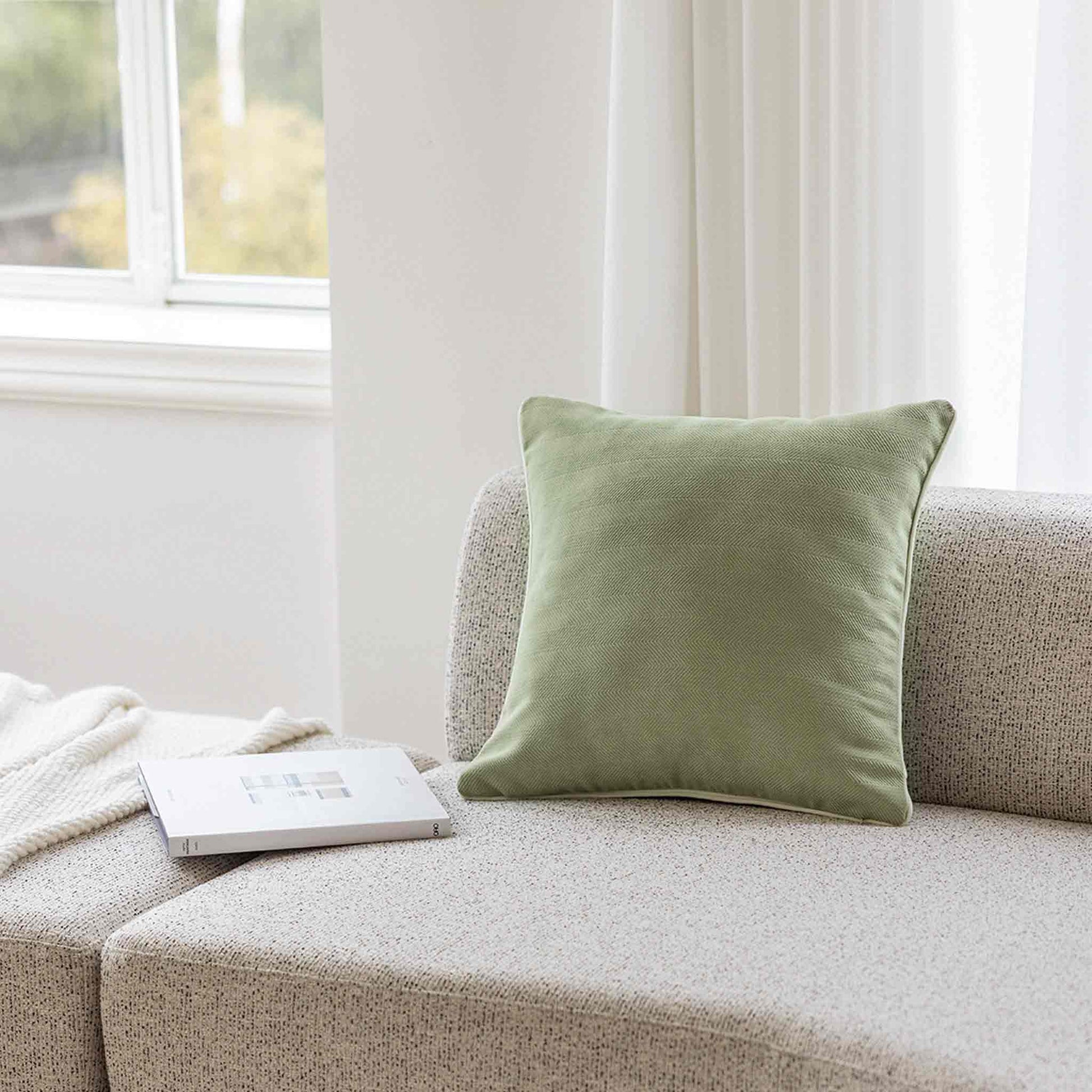 Mint green herringbone, white wrapped chenille cushion on grey sofa.