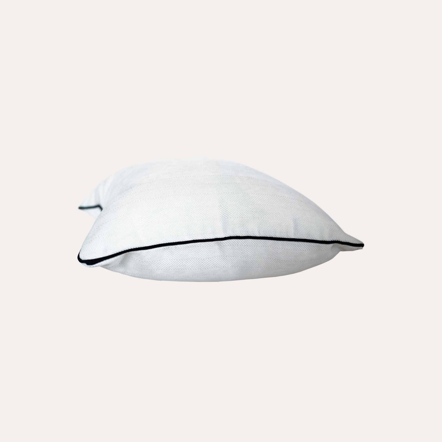 A stylish white cushion cover with black piping, designed with a herringbone texture.