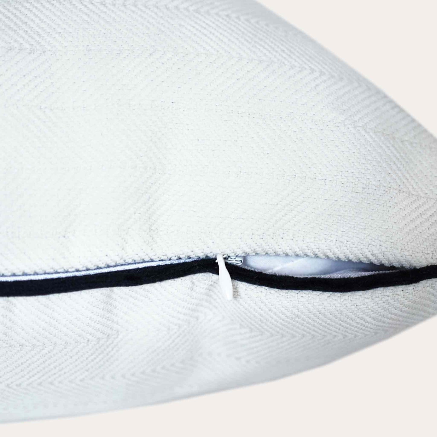 A stylish white cushion cover with black piping, designed with a herringbone texture and invisible zipper.