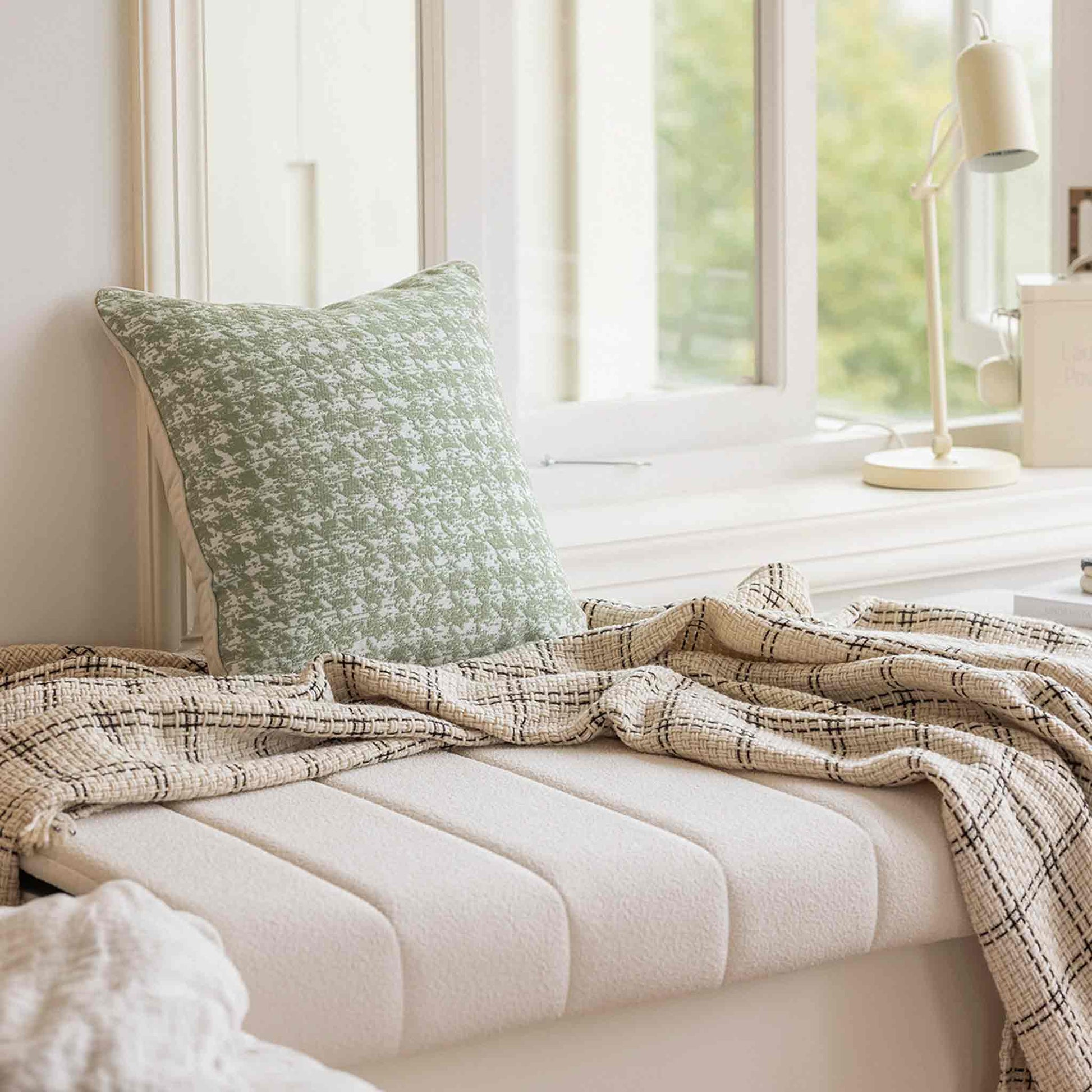 A green and white houndstooth pattern soft chenille cushion on white sofa.