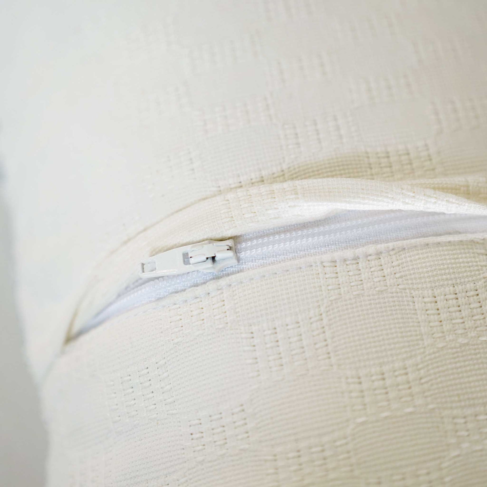 Close-up of the invisible zip on the white textured lumbar cushion.