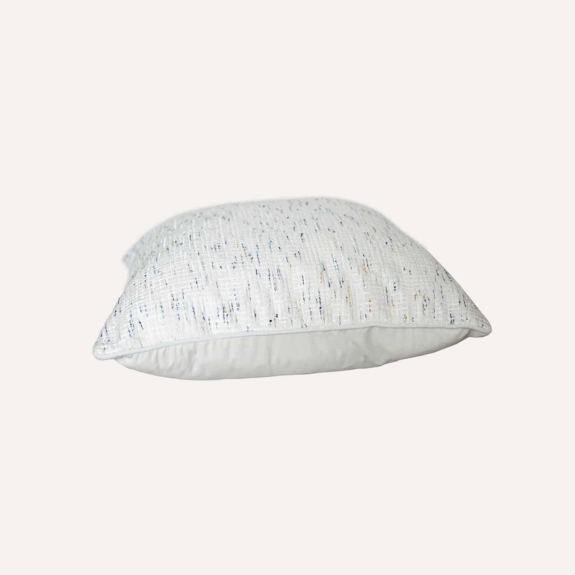 An ivory base cushion cover decorated with blue and yellow colored dots.