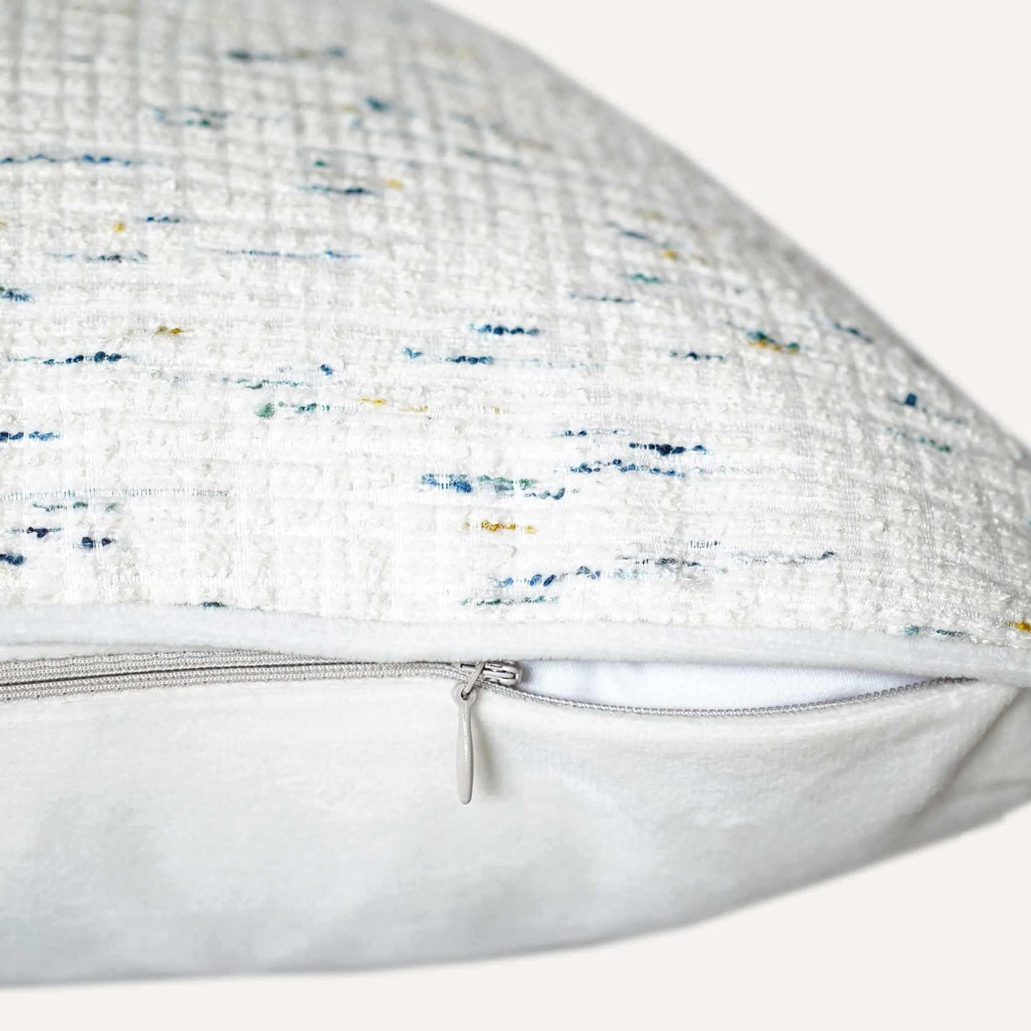 An ivory base cushion cover decorated with blue and yellow colored dots with invisible zipper.