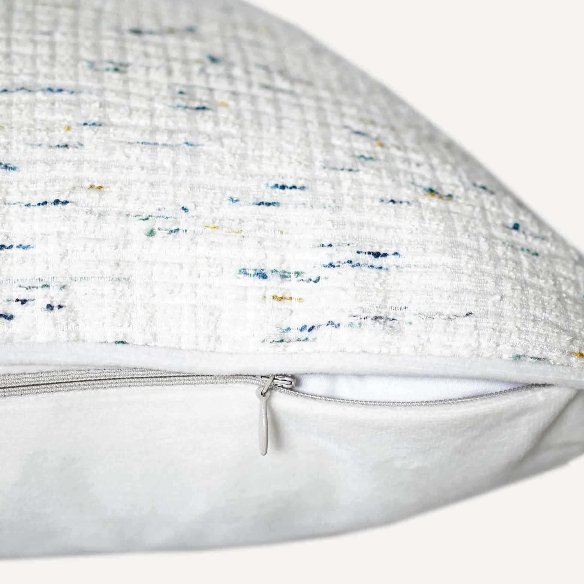 An ivory base cushion cover decorated with blue and yellow colored dots with invisible zipper.