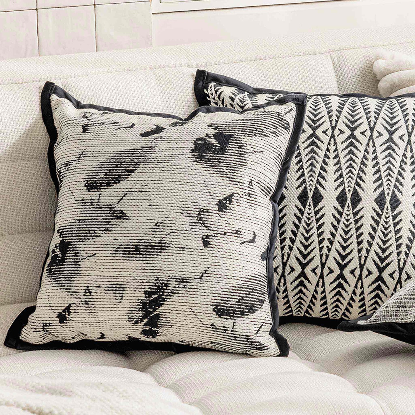 Black and white abstract shadow pattern cushion on white sofa.