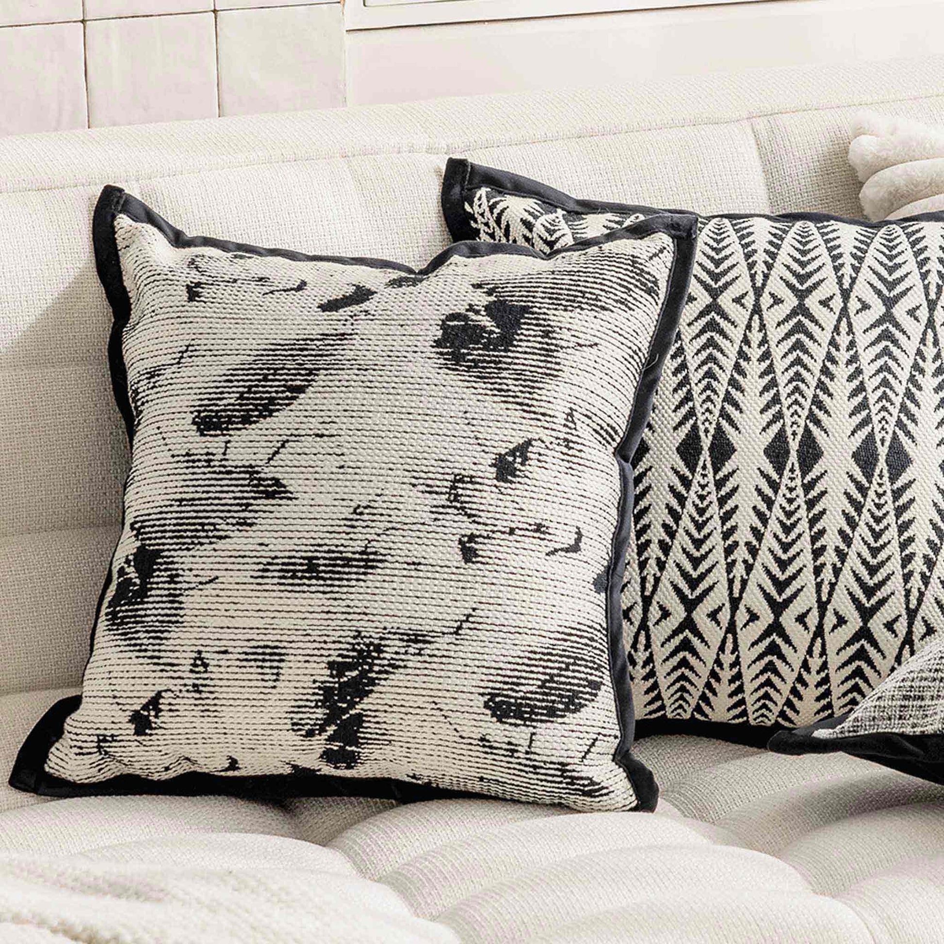 Black and white abstract shadow pattern cushion on white sofa.