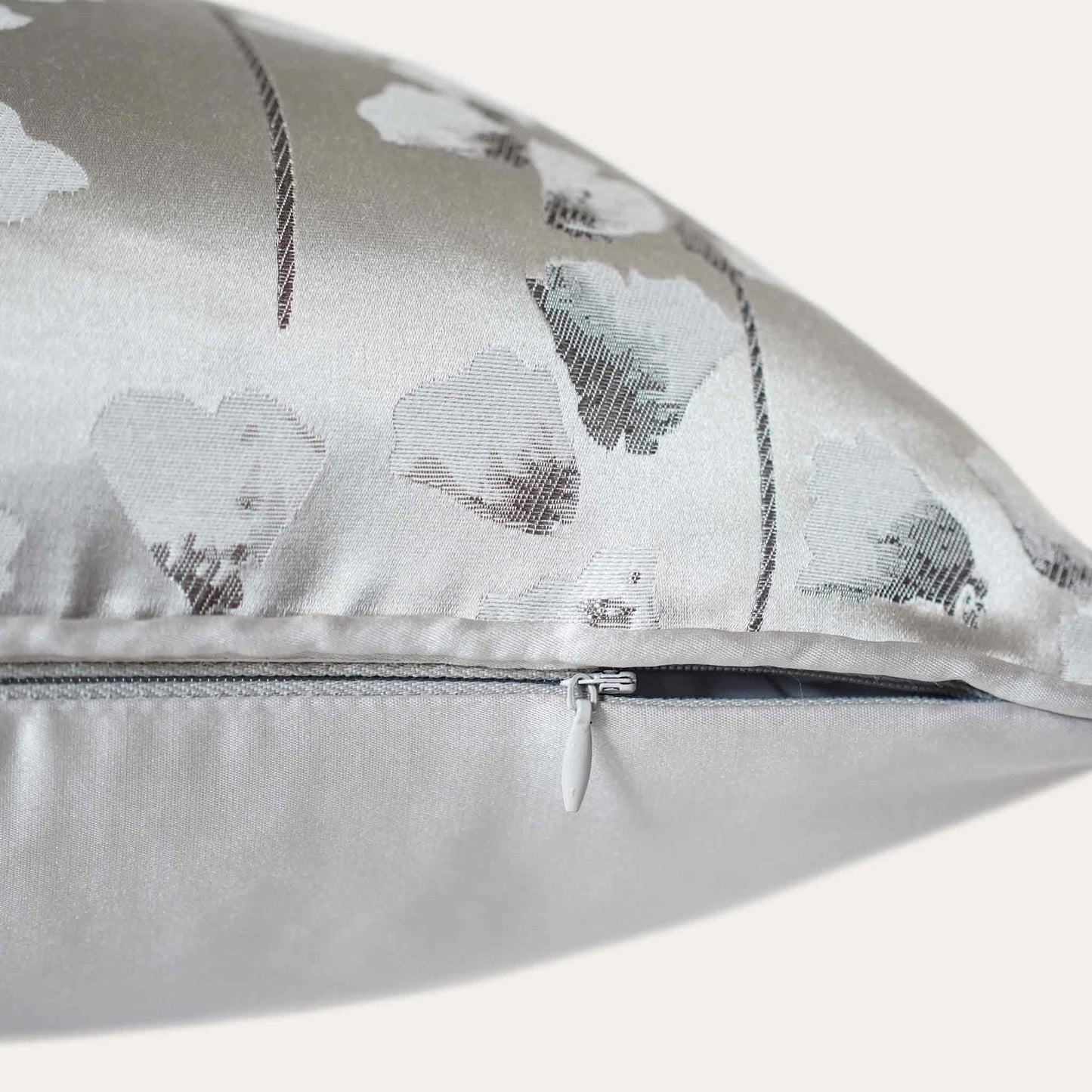 A chic silver cushion cover adorned with intricate off-white jacquard floral designs with invisible zipper.