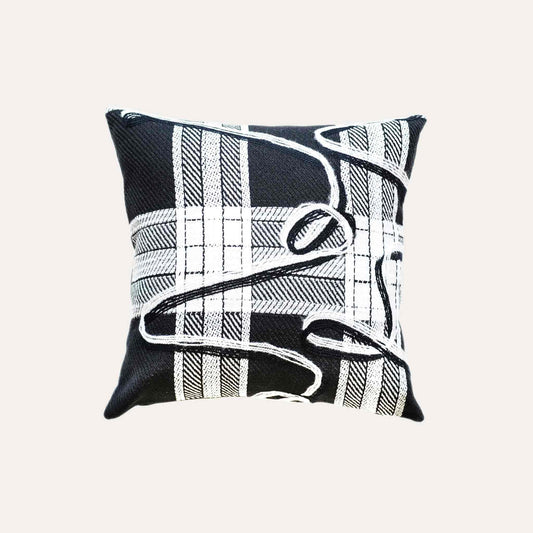 A black and white plaid and ribbon cushion cover.