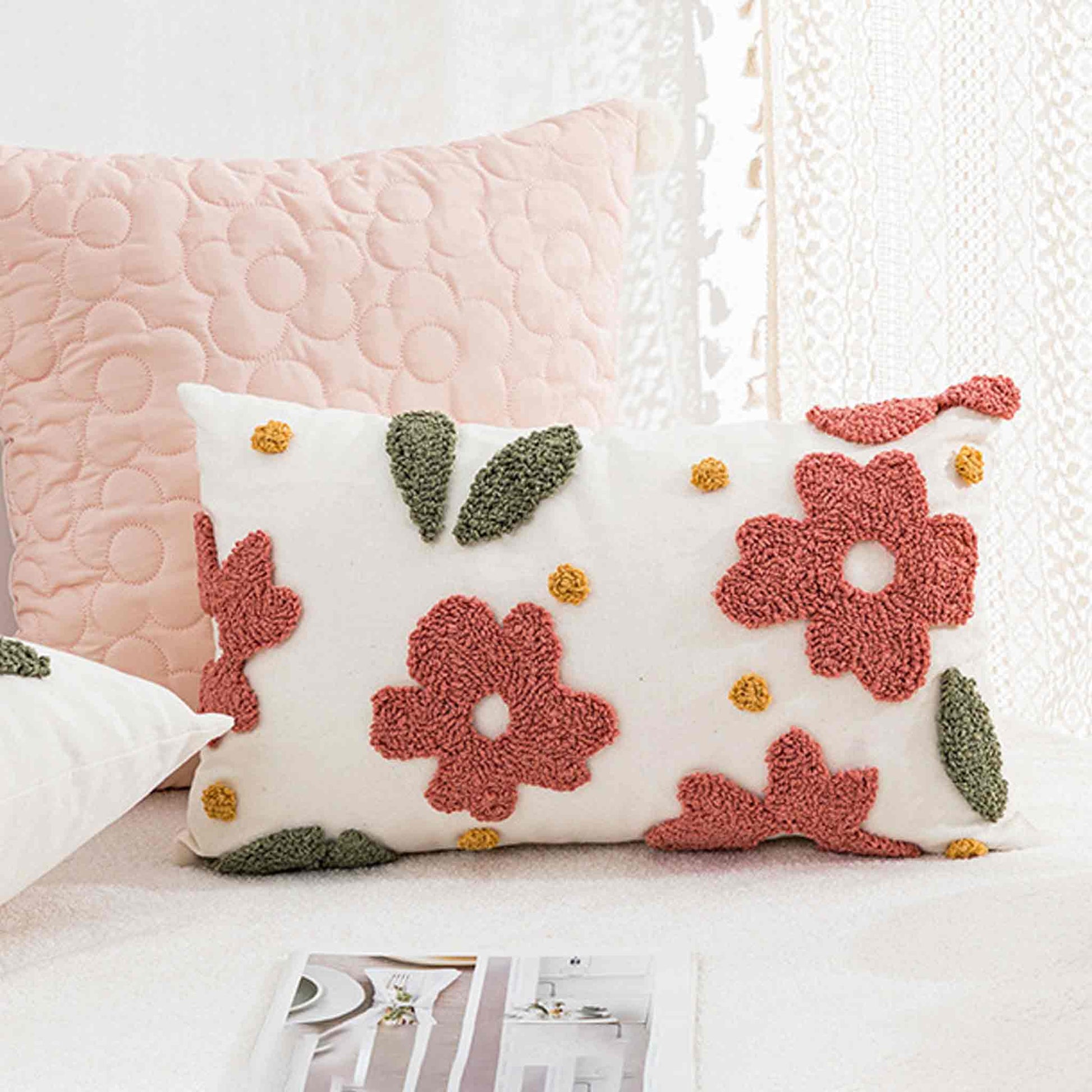 Decorative cushion with floral pattern on a white sofa, accompanied by a pink cushion.