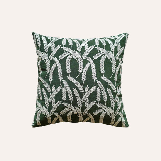 White straw embroidered cushion cover with dark green background.