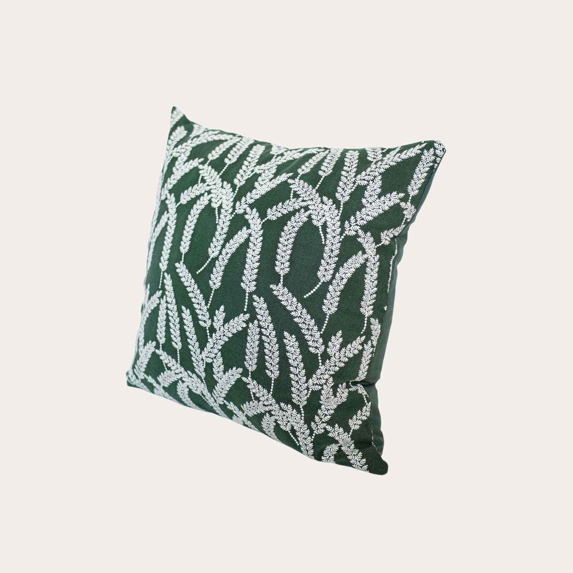 White straw embroidered cushion cover with dark green background.