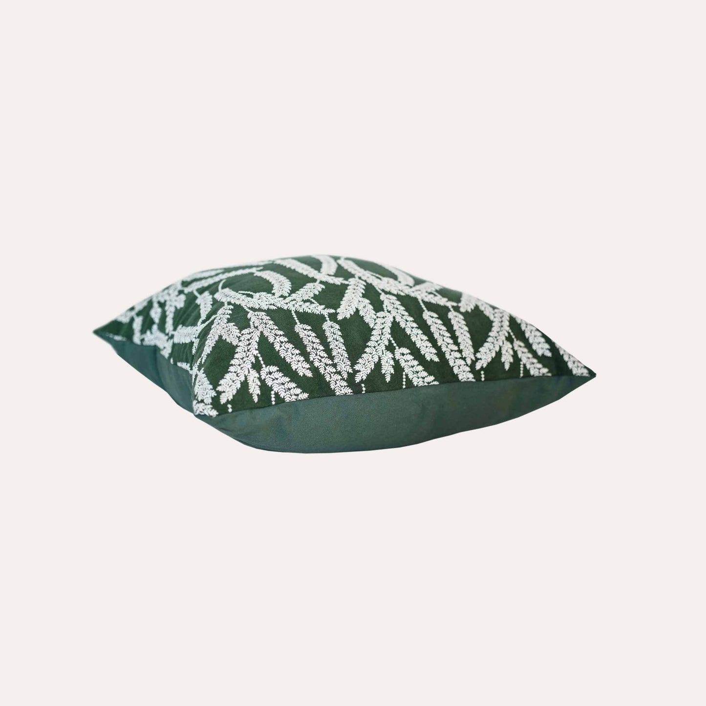 White straw embroidered cushion cover with dark green background.