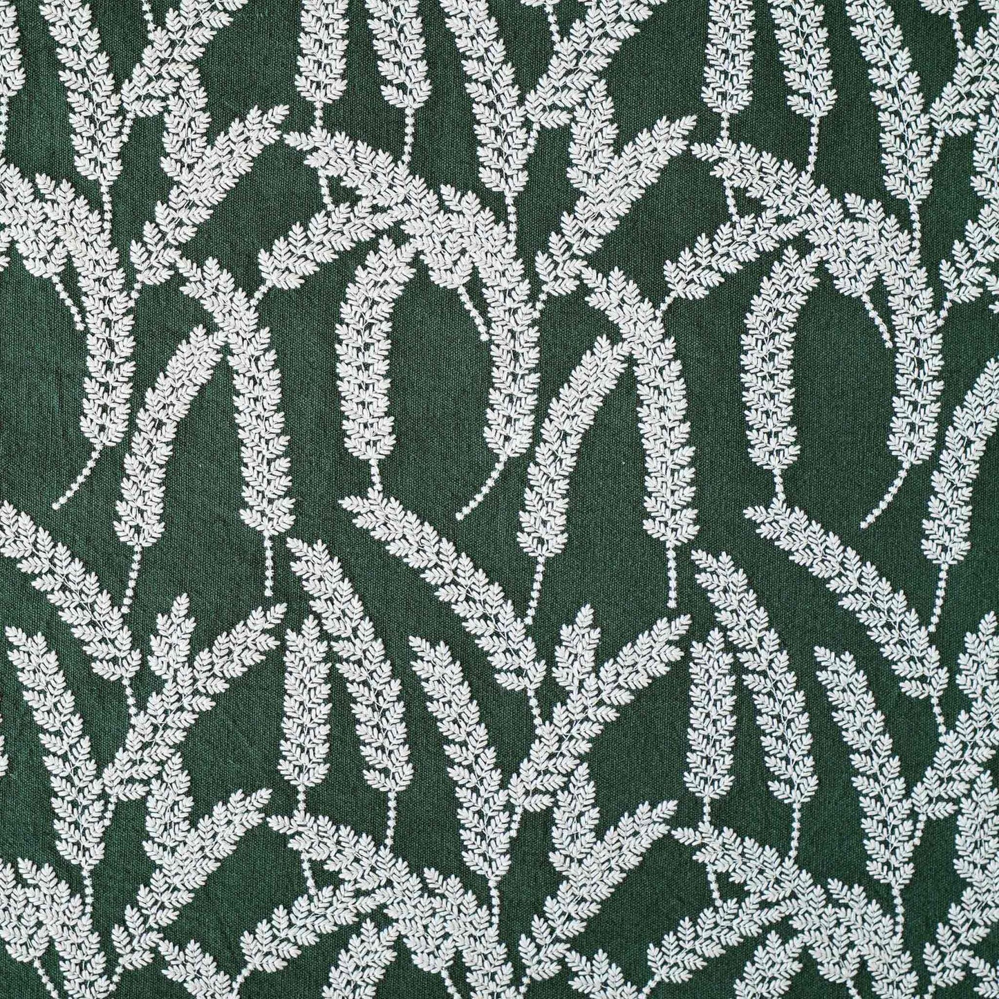 White straw embroidered cushion cover with dark green background.