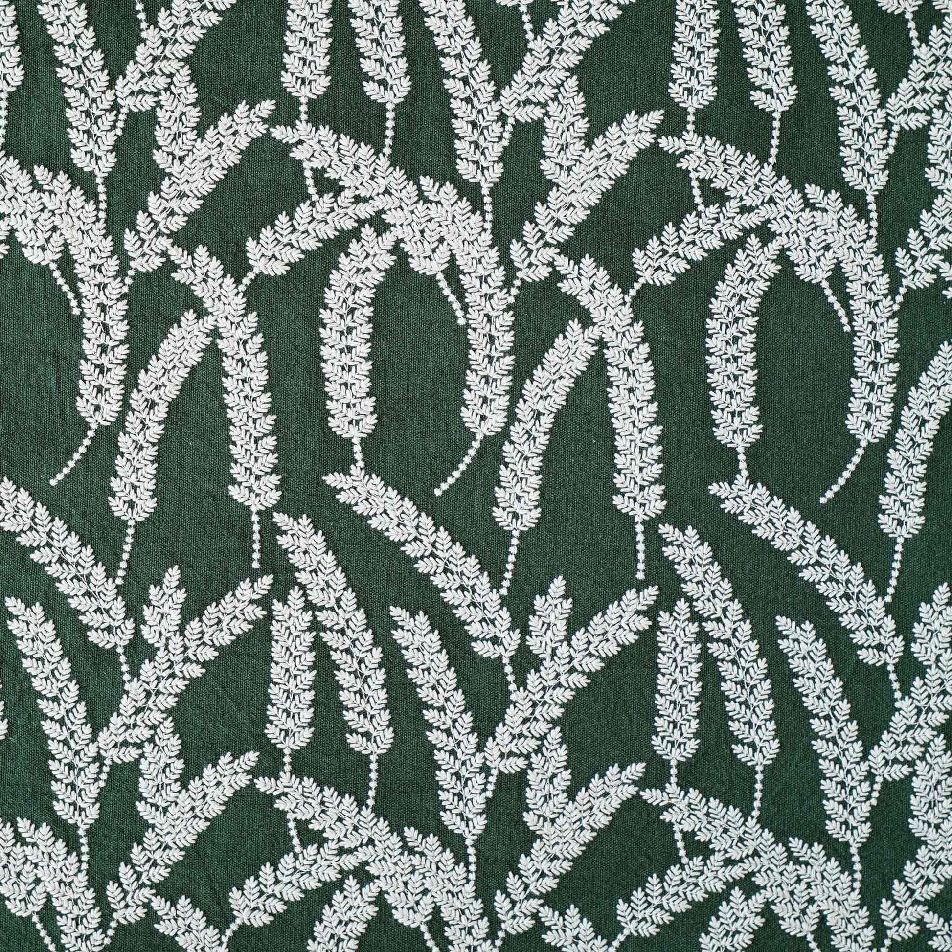 White straw embroidered cushion cover with dark green background.