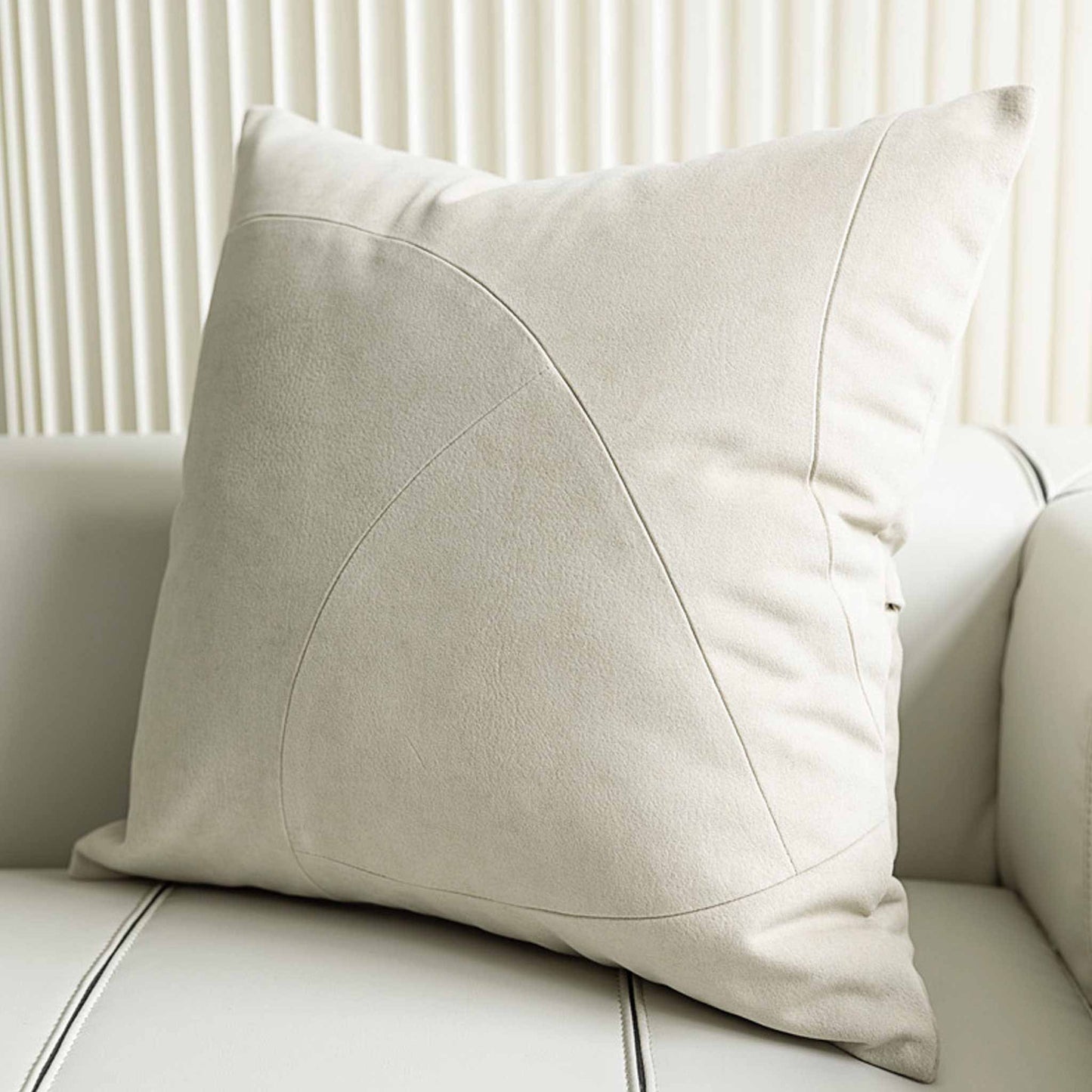 Chic white curved patchwork cushion cover on white sofa.