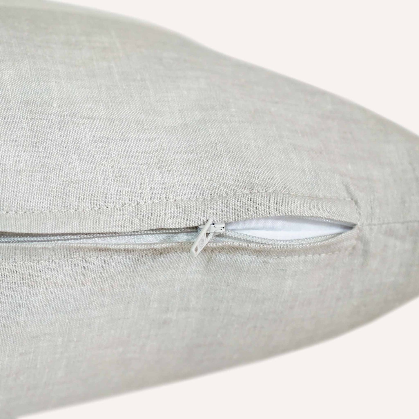 A close-up view of a cushion featuring a visible zipper along one edge.